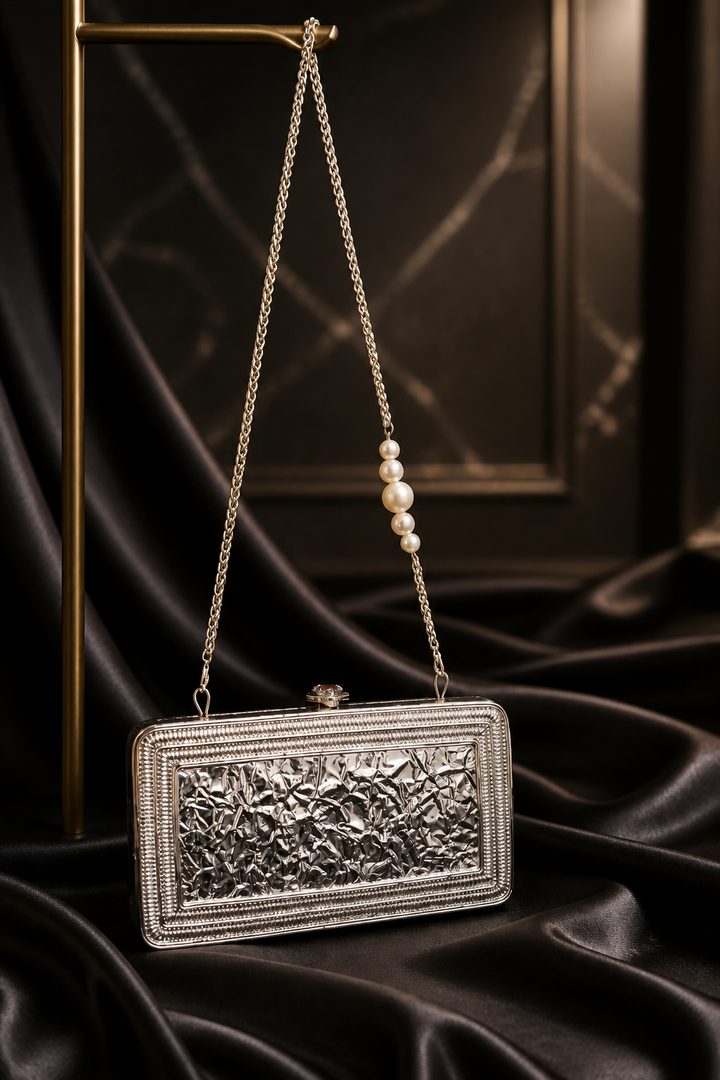 Luxury Meenakari filigree clutch bag with intricate floral metal detailing, colourful stone embellishments, and pearl chain sling design