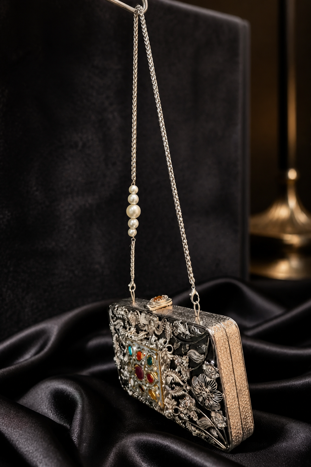 Luxury Meenakari filigree clutch bag with intricate floral metal detailing, colourful stone embellishments, and pearl chain sling design