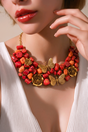 Statement coral tumble necklace with butterfly charms, floral motifs, and antique gold detailing with matching earrings
