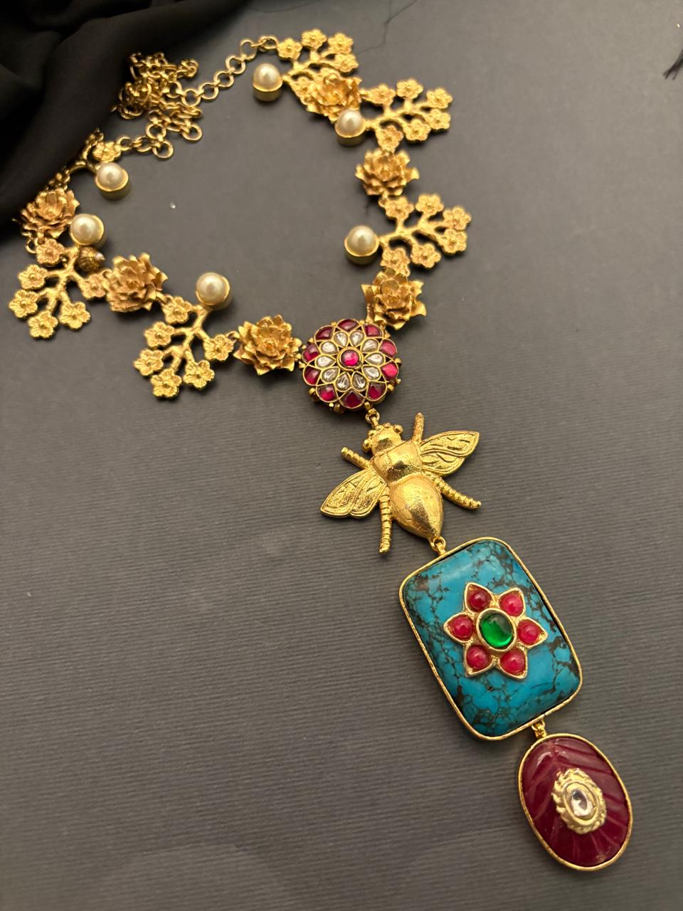 Designer bug motif necklace with turquoise pendant and intricate gold detailing in artistic ethnic jewellery style