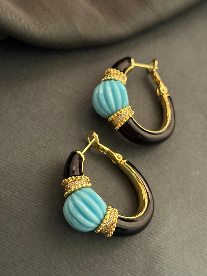 Designer earrings with carved turquoise stones and black enamel detailing in contemporary ethnic style