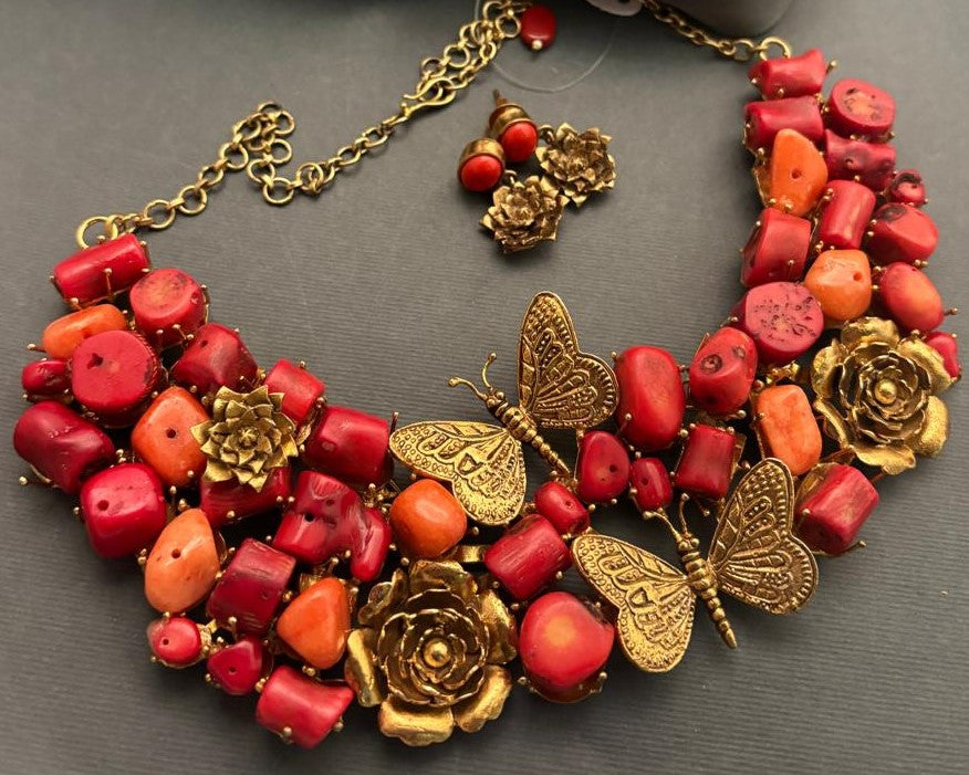 Statement coral tumble necklace with butterfly charms, floral motifs, and antique gold detailing with matching earrings