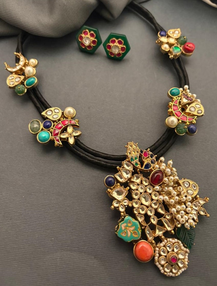 Black cord statement necklace with multicolor stones, jadau motifs, pearl detailing, and matching stud earrings in antique gold finish