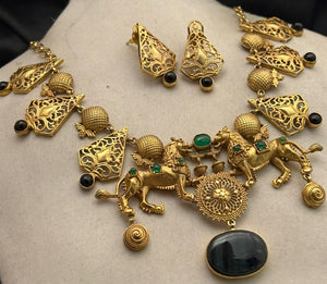 Antique gold lion motif statement necklace with black onyx stone pendant, intricate filigree detailing, and matching designer earrings on a black background