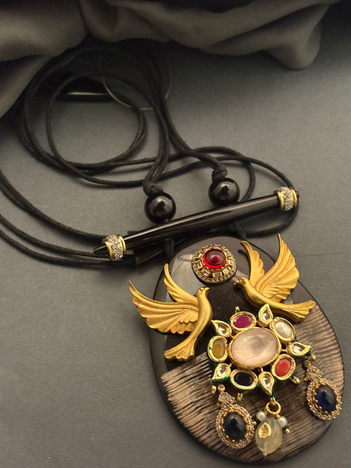 Handcrafted resin pendant with bird motif, kundan detailing, and coloured stones on black thread necklace