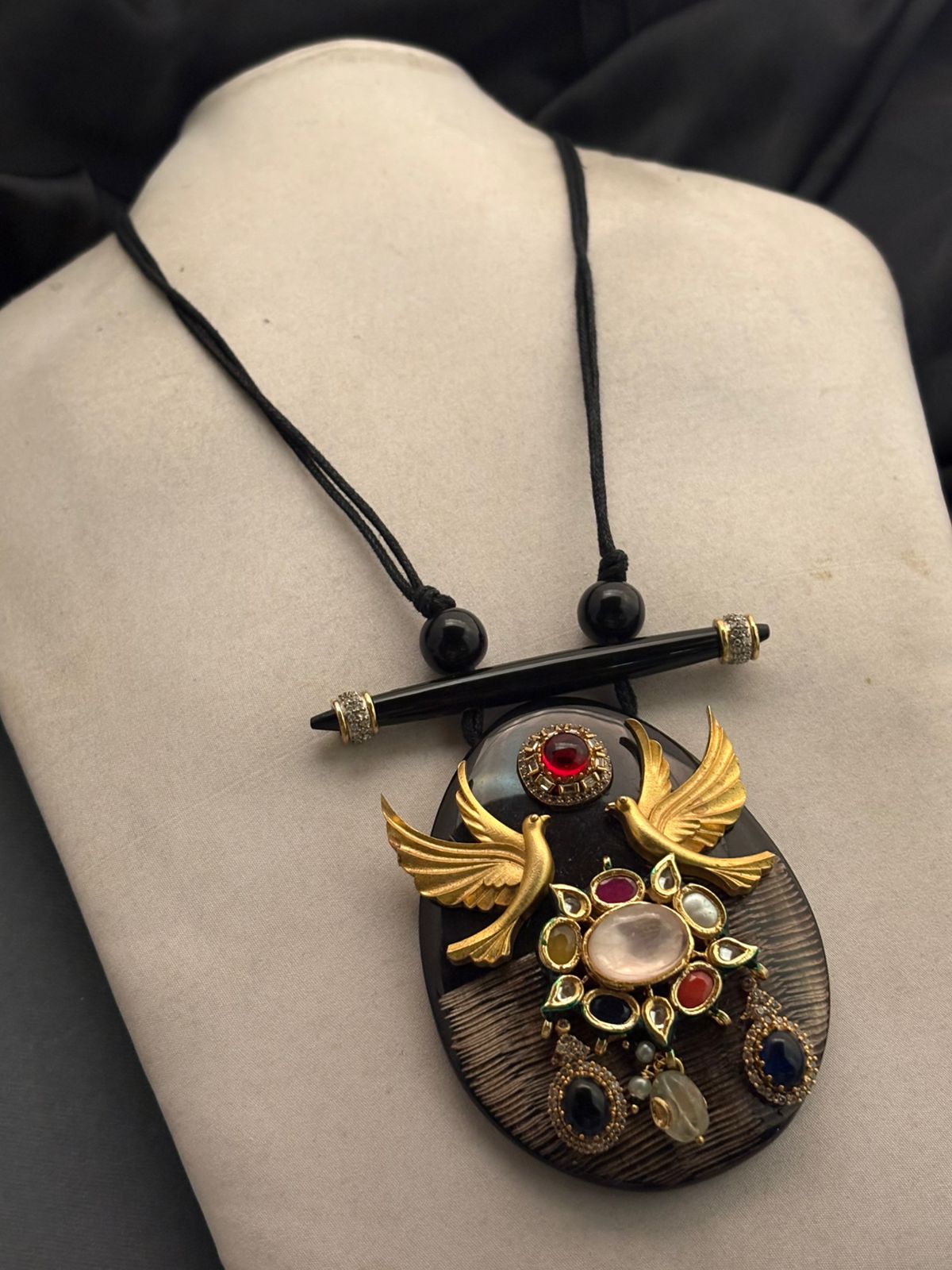 Handcrafted resin pendant with bird motif, kundan detailing, and coloured stones on black thread necklace