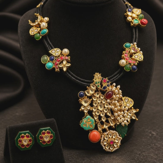 Black cord statement necklace with multicolor stones, jadau motifs, pearl detailing, and matching stud earrings in antique gold finish