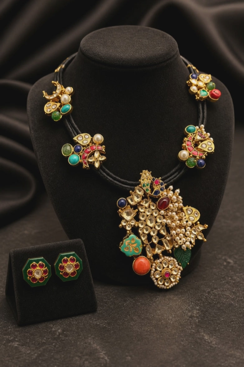 Black cord statement necklace with multicolor stones, jadau motifs, pearl detailing, and matching stud earrings in antique gold finish