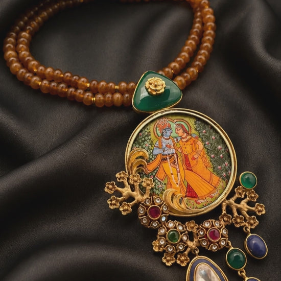 Miniature painting necklace with Radha Krishna artwork, kundan crystal detailing, and brown bead strands in traditional ethnic jewellery style