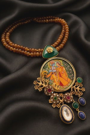 Miniature painting necklace with Radha Krishna artwork, kundan crystal detailing, and brown bead strands in traditional ethnic jewellery style