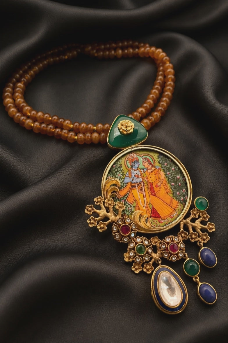 Miniature painting necklace with Radha Krishna artwork, kundan crystal detailing, and brown bead strands in traditional ethnic jewellery style