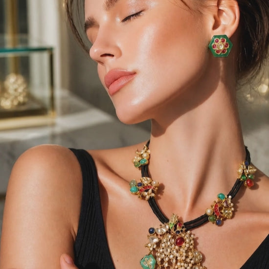 Black cord statement necklace with multicolor stones, jadau motifs, pearl detailing, and matching stud earrings in antique gold finish