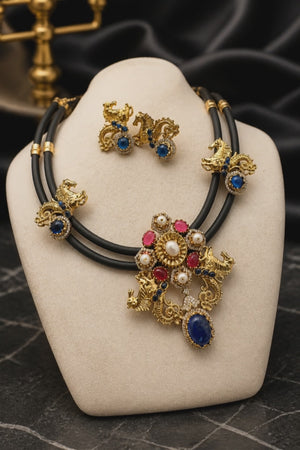 Antique gold horse motif necklace on black cord with blue and pink stones, pearl detailing, and matching designer earrings displayed on a jewellery bust