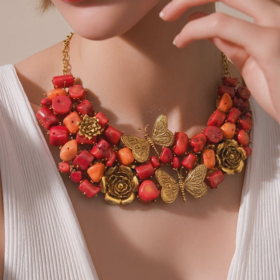 Statement coral tumble necklace with butterfly charms, floral motifs, and antique gold detailing with matching earrings