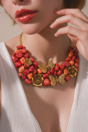 Statement coral tumble necklace with butterfly charms, floral motifs, and antique gold detailing with matching earrings