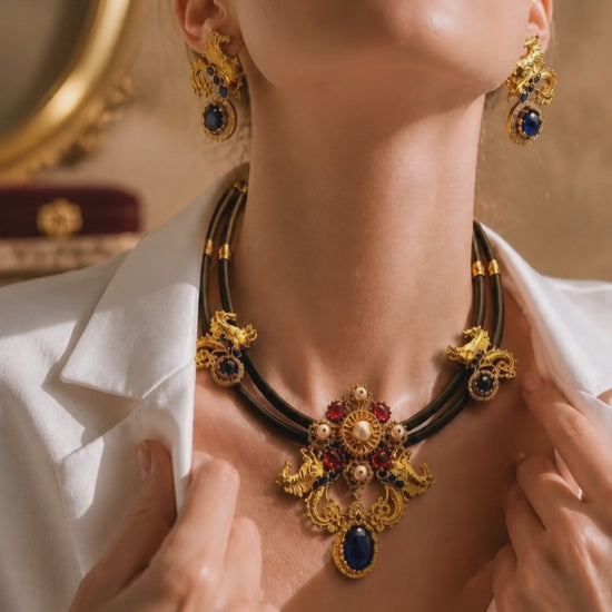 Antique gold horse motif necklace on black cord with blue and pink stones, pearl detailing, and matching designer earrings displayed on a jewellery bust