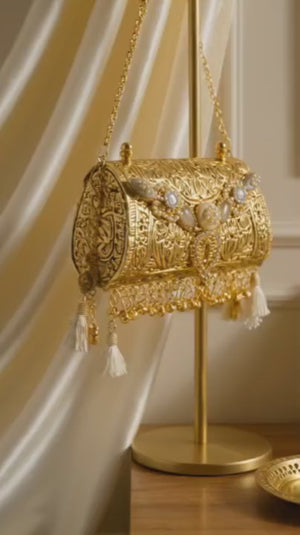 Luxury Alaka mini bag with intricate gold embossed detailing, crystal embellishments, tassels, and metallic handle design
