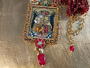 Decorative pendant with intricate design and red gemstones on a gold surface